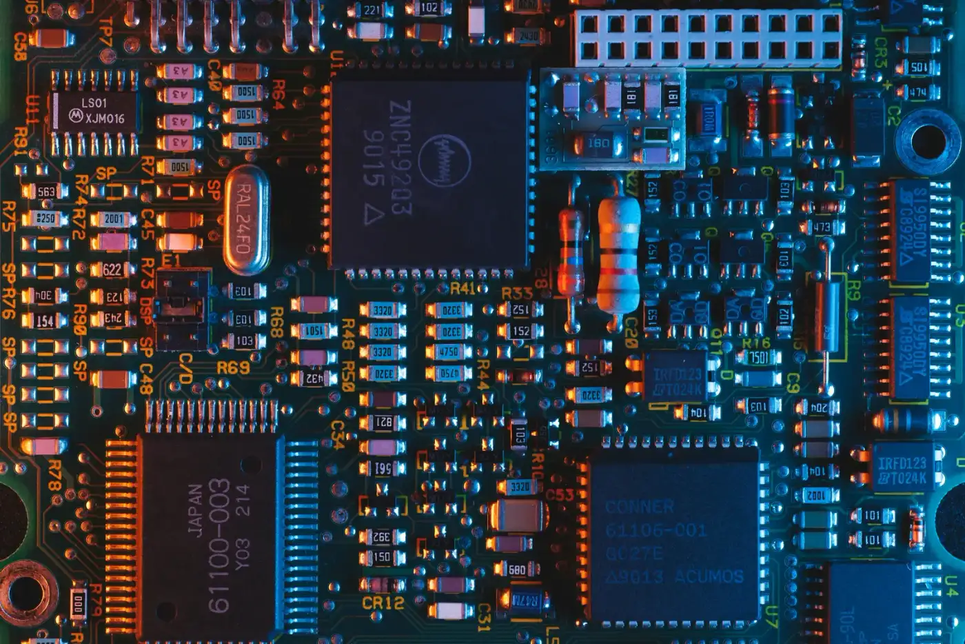 Nahaufnahme einer Platine mit elektronischen Bauteilen in Blau- und Orangetönen