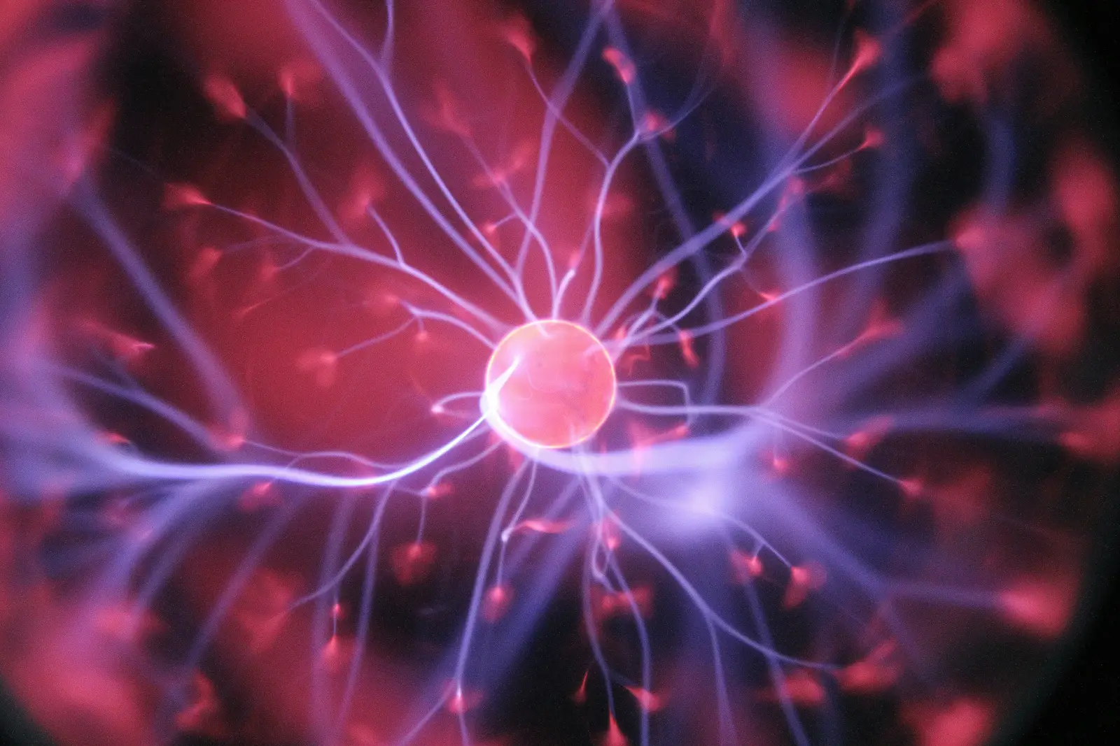 Leuchtende Plasma-Kugel vor dunklem Hintergrund, elektrische Entladungen sichtbar